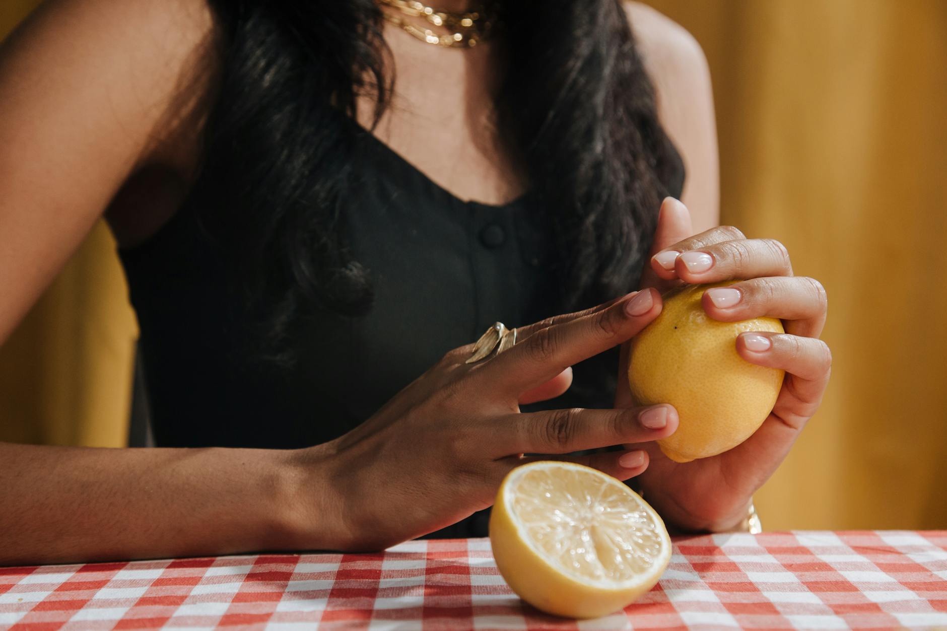 Close-up of woman holding fresh lemon at dining table