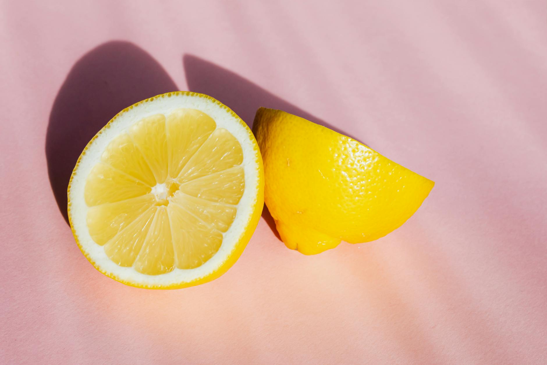 Fresh lemons on a pink background in bright sunlight, symbolizing vitality and freshness amid calm surroundings