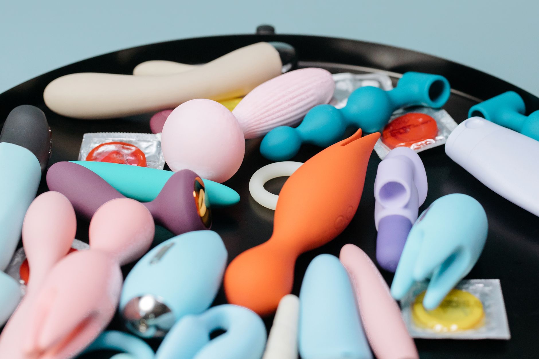 A collection of various adult toys on a black tray, showcasing diverse shapes and gentle design options