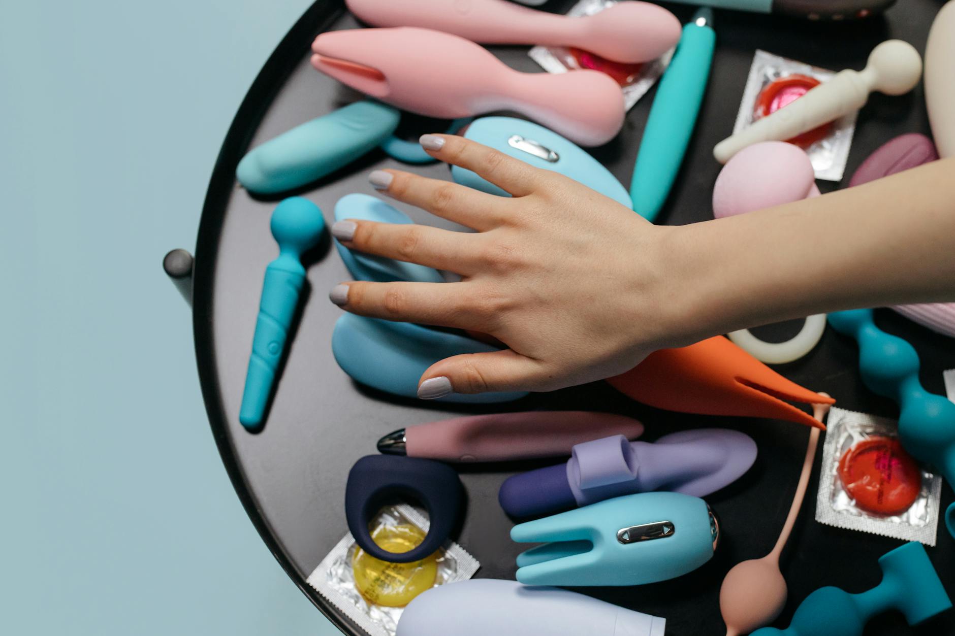 Woman holding a blue clitoral vibrator with a thoughtful expression