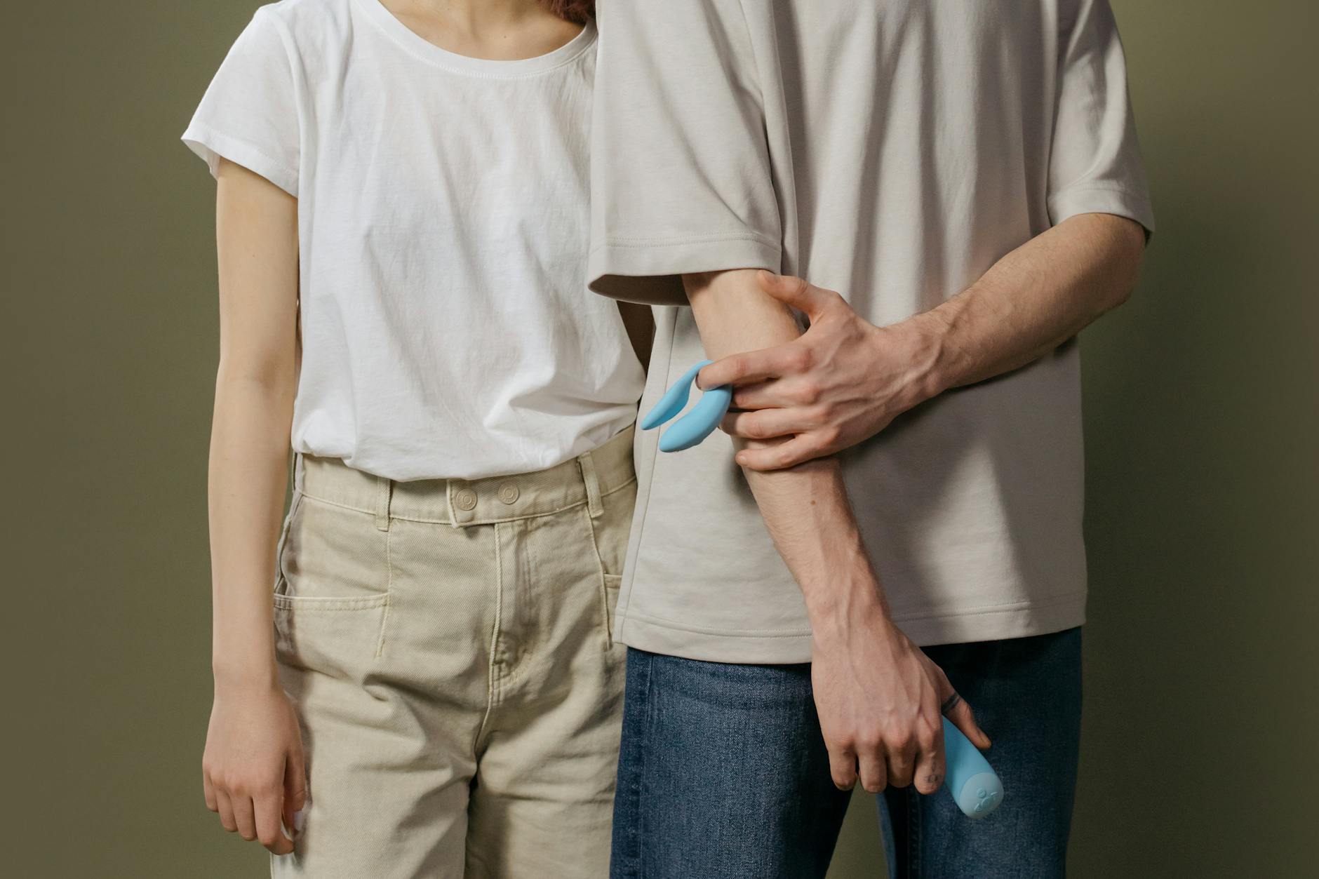 A blue silicone vibrator held gently in hand against a purple background