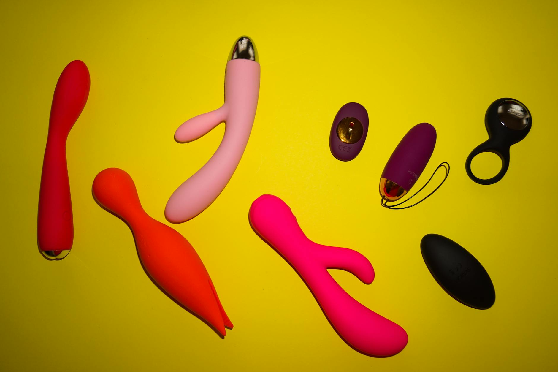 A hand holding a sleek orange vibrator against a minimalist purple backdrop