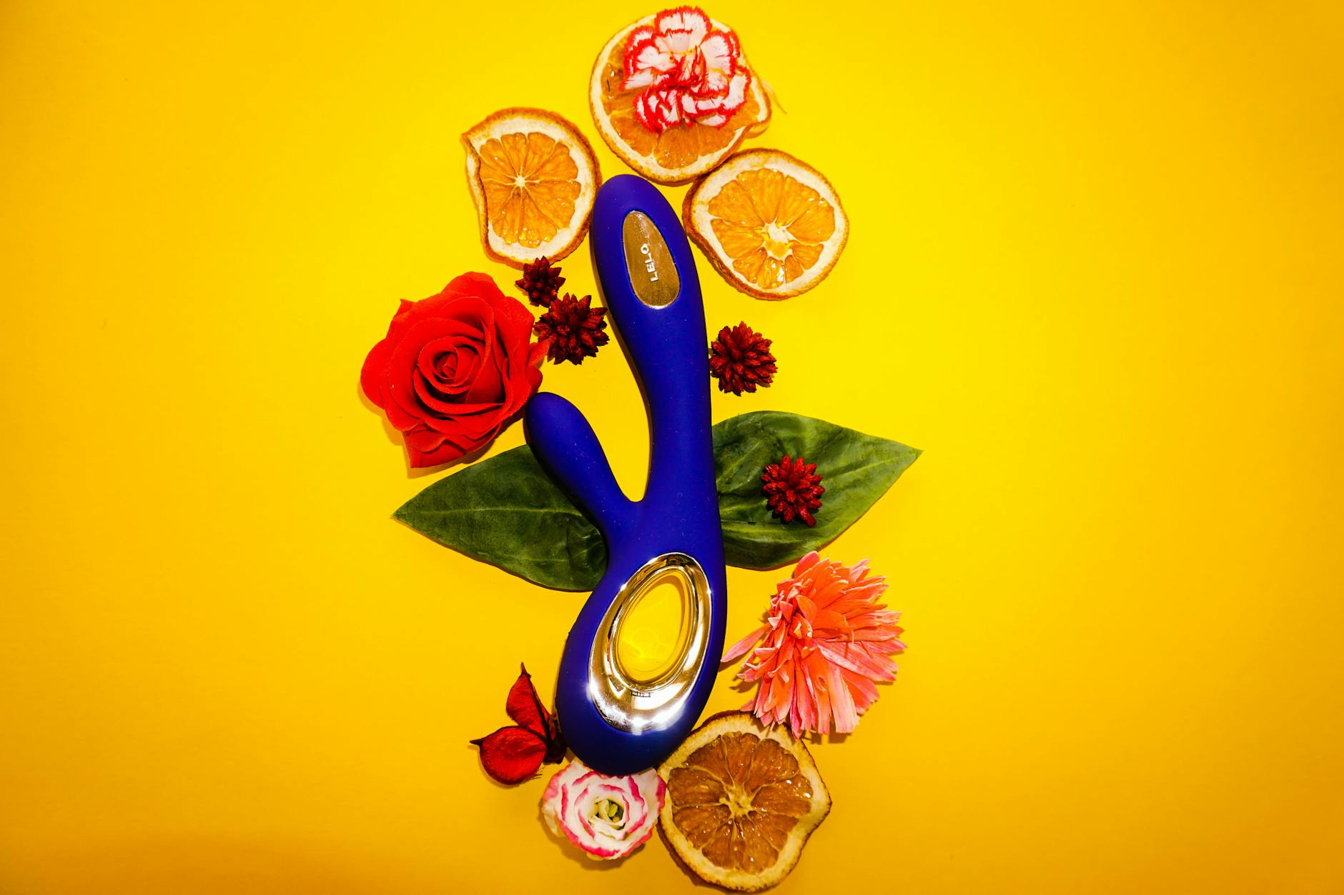 Hand holding an orange vibrator against a purple backdrop, showcasing modern sensuality and intimate wellness