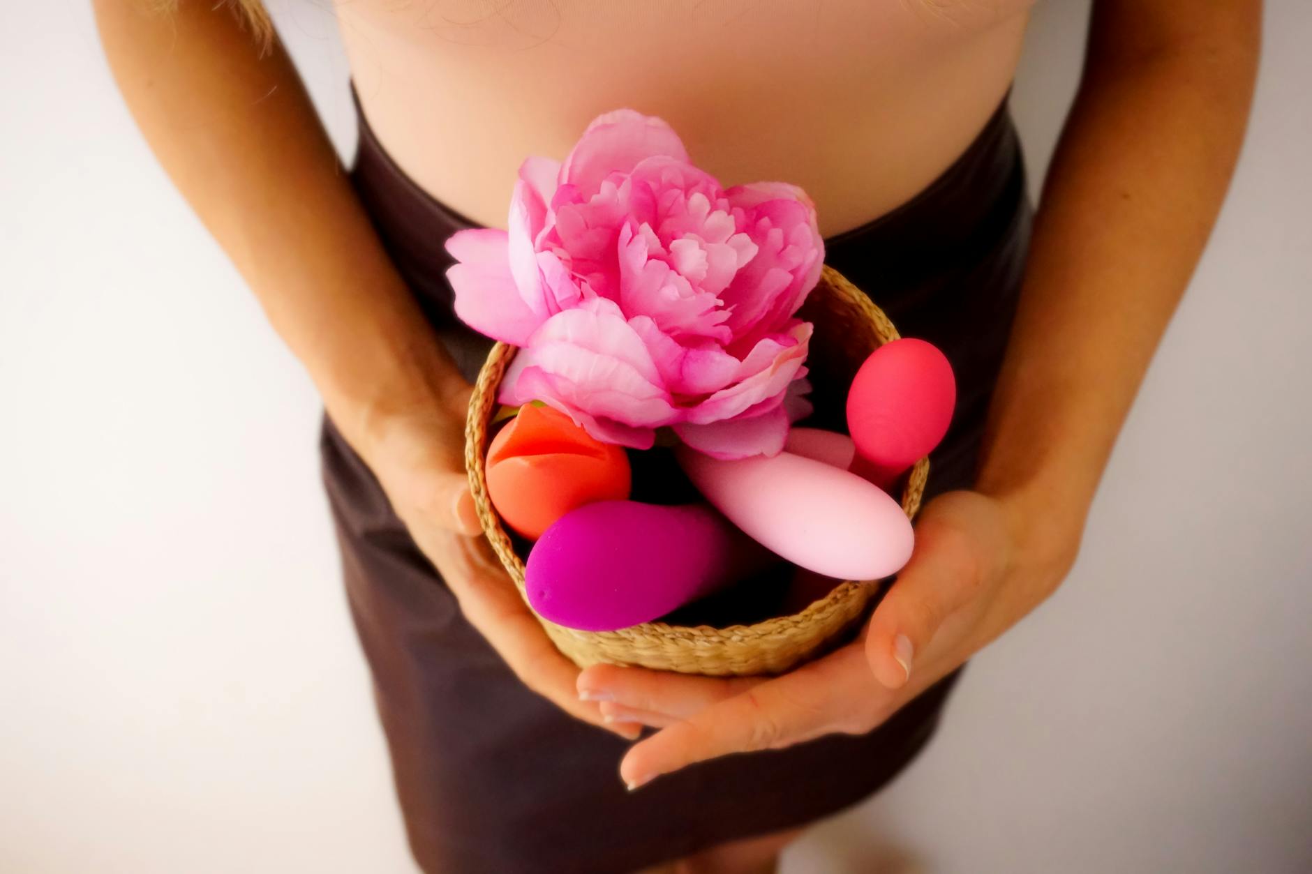 Blue clitoral vibrator surrounded by flowers and citrus on a bright yellow background